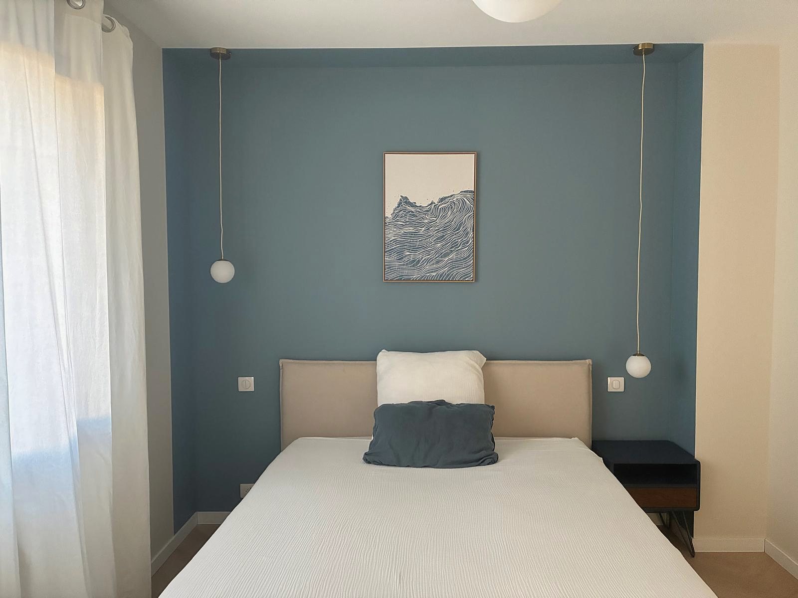 La chambre de La petite vague, mur bleu et lit fait