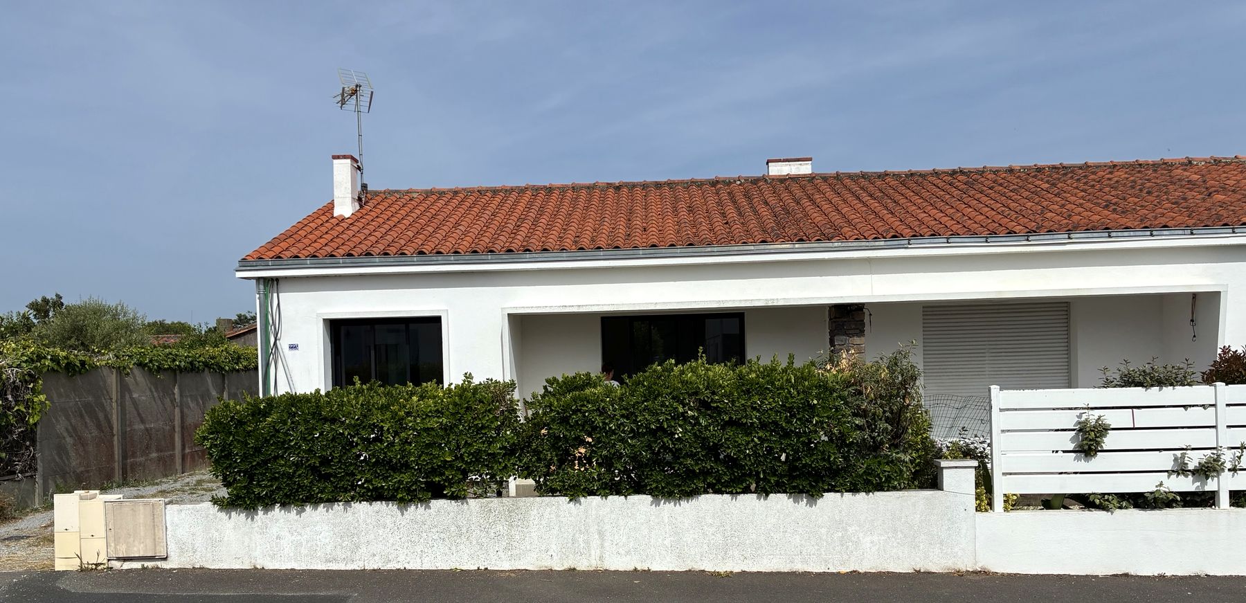 La maison vue depuis la rue, façade blanche et toit de tuiles