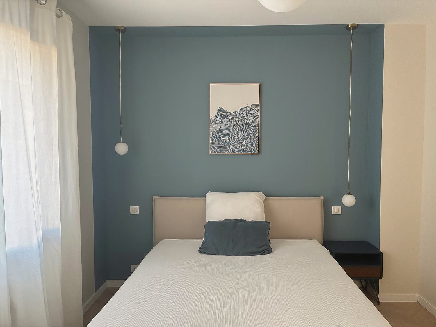 La chambre, mur bleu, lit fait et coussin de lin