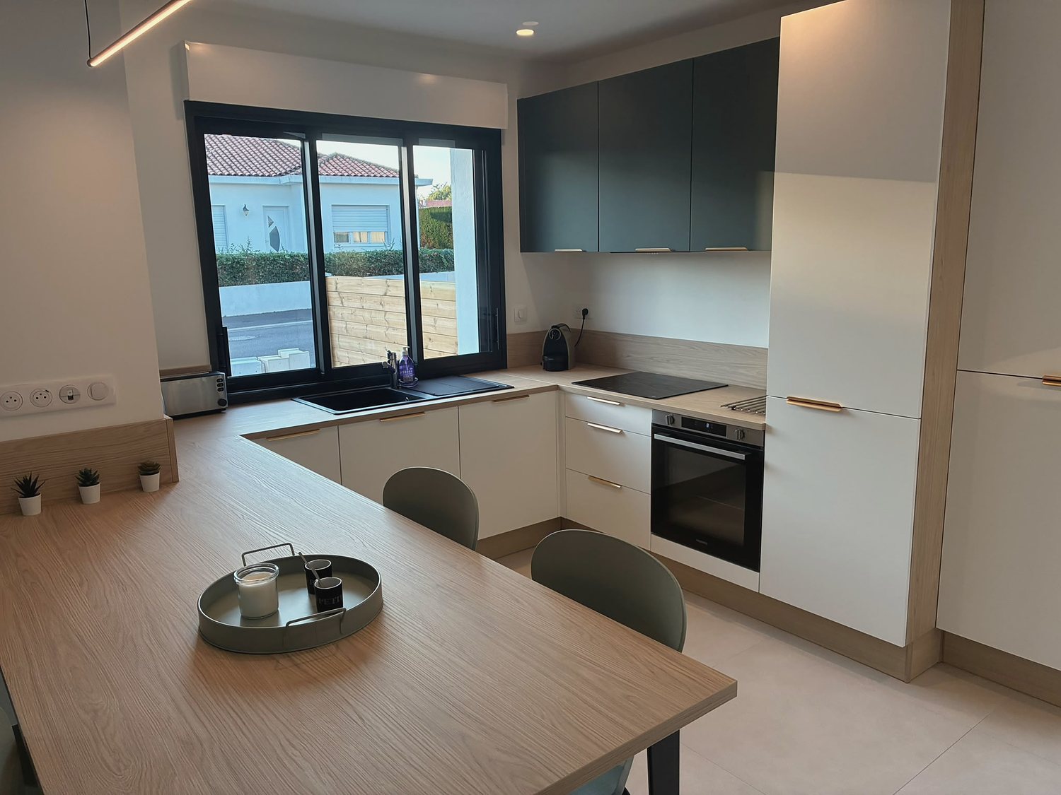 La cuisine ouverte et la grande table de bois clair