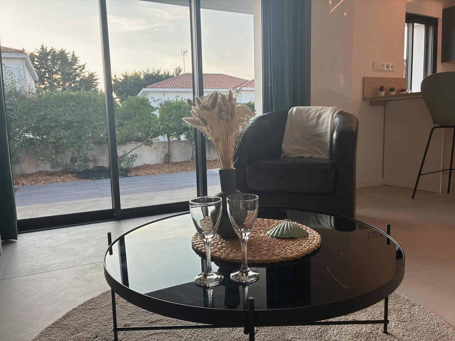 Le séjour au coucher du soleil, fauteuil et table basse devant la baie